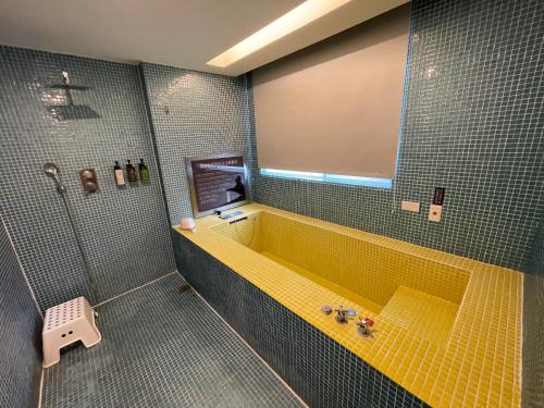 a bathroom with a yellow tub and a shower at Ya Nold Hot Spring Hotel in Jiaoxi
