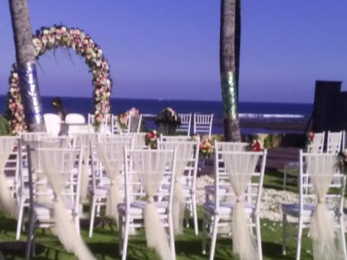 a row of white chairs with the ocean in the background at Villa Samudra Luxury Beachfront in Ketewel
