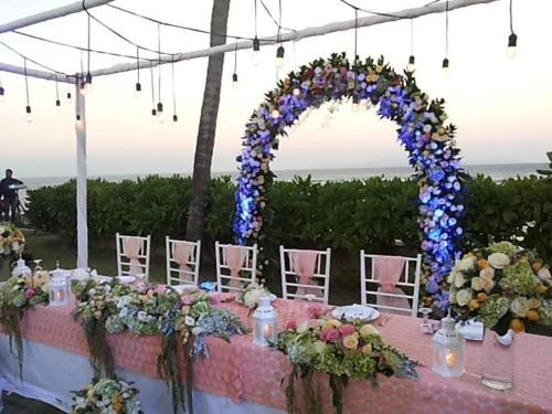 a table with an arch and chairs with flowers at Villa Samudra Luxury Beachfront in Ketewel