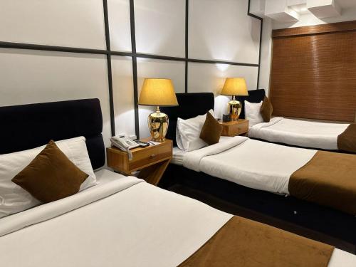 um quarto de hotel com duas camas e duas lâmpadas em Lawrence View Hotel em Lahore