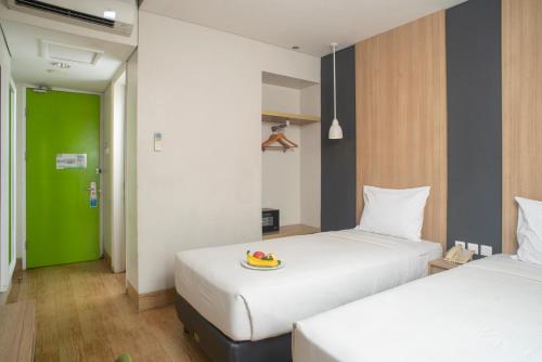 a room with two beds with a plate of fruit on it at Hotel Citradream Semarang in Semarang