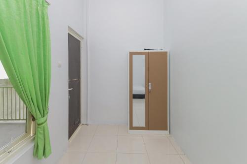 a room with a door and a green curtain at KoolKost Syariah near Alun Alun Sidoarjo in Sidoarjo
