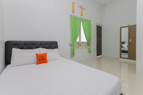 a bedroom with a large bed with an orange pillow at KoolKost Syariah near Alun Alun Sidoarjo in Sidoarjo