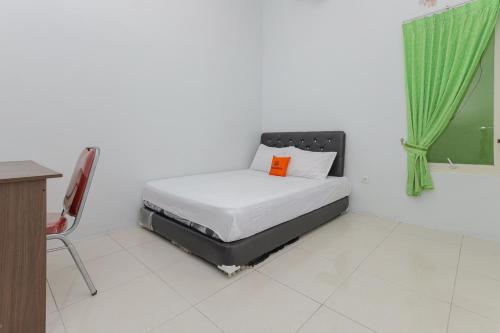 a bedroom with a bed with an orange pillow on it at KoolKost Syariah near Alun Alun Sidoarjo in Sidoarjo
