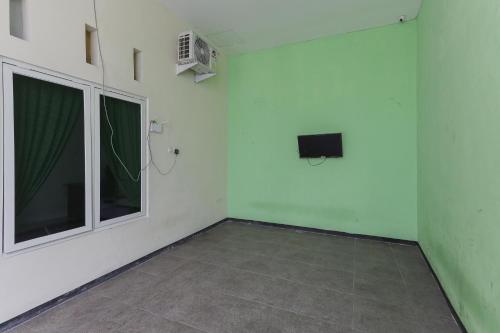 an empty room with a television and a window at KoolKost Syariah near Alun Alun Sidoarjo in Sidoarjo