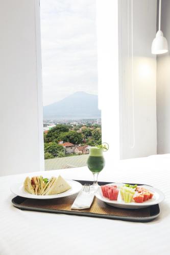two plates of food on a table with a window at Hotel Citradream Cirebon in Cirebon