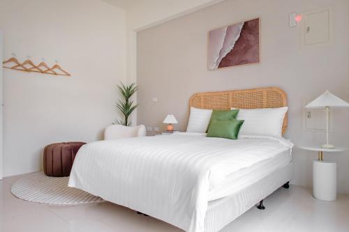 a white bedroom with a large white bed with green pillows at Taitung Chun Yang Inn in Taitung City