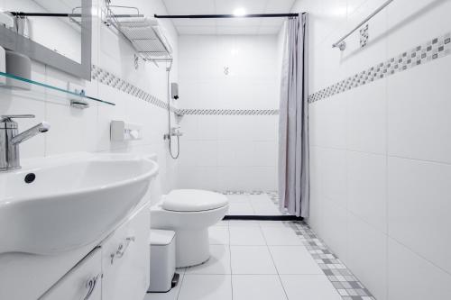 a white bathroom with a toilet and a sink at Taitung Chun Yang Inn in Taitung City