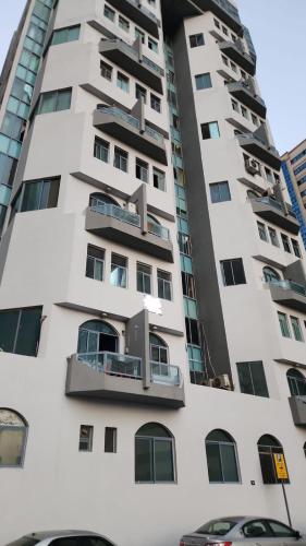 a tall white apartment building with a balcony at Gulf building, homestay in Sharjah