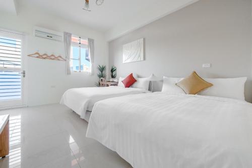two beds in a white room with white walls at Taitung Chun Yang Inn in Taitung City