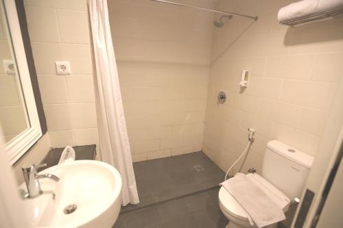 y baño con lavabo, aseo y ducha. en Hotel Citradream Cirebon en Cirebon
