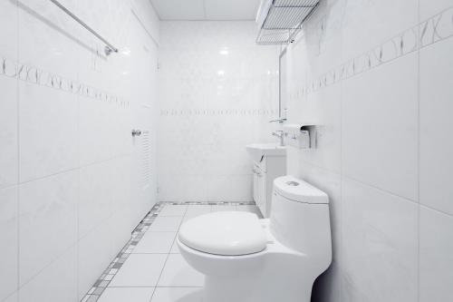 a white bathroom with a toilet and a sink at Taitung Chun Yang Inn in Taitung City