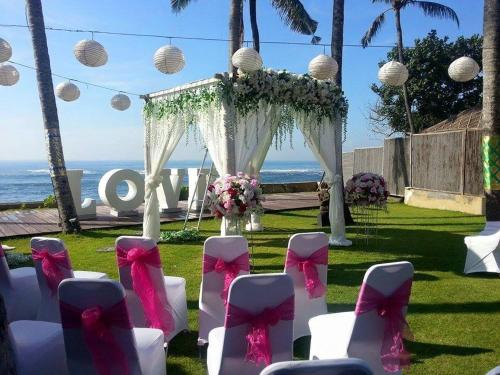 a wedding ceremony with white chairs and pink bows at Villa Samudra Luxury Beachfront in Ketewel