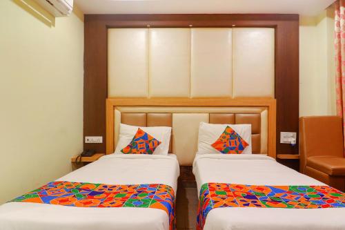 a bedroom with two beds with colorful pillows at FabHotel Keerthi's Anupama - Nr Indira Gandhi Stadium in Vijayawāda