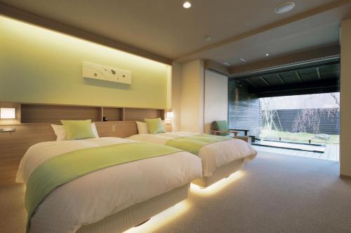 a bedroom with two beds and a large window at Yuuyu No Sato Yusa in Yamagata