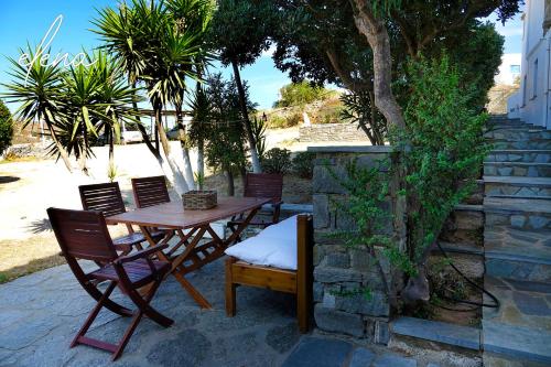 a wooden table and chairs sitting next to a stone wall at Elena Studios & Apartments in Piso Livadi