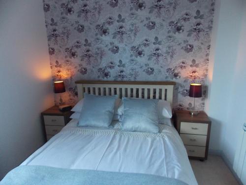 um quarto com uma cama com almofadas azuis e papel de parede floral em Waterside Apartment em Lancaster