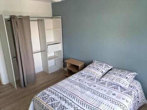 a bedroom with a bed with a white and black blanket at Très bel appartement proche parc des expositions et aéroport Roissy CDG in Villepinte