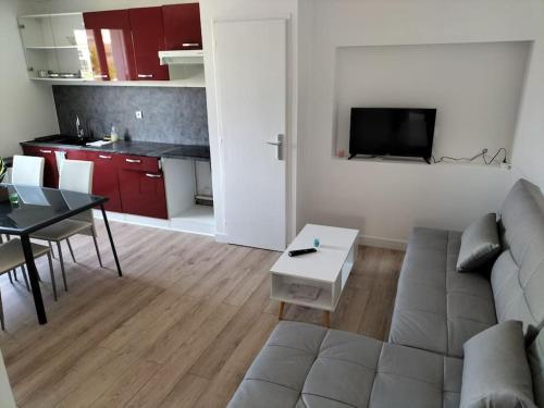 a living room with a couch and a table and a kitchen at Très bel appartement proche parc des expositions et aéroport Roissy CDG in Villepinte