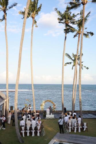a wedding ceremony on the beach with palm trees at Villa Samudra Luxury Beachfront in Ketewel