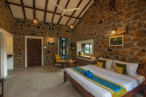 a bedroom with a large bed in a stone room at SaffronStays Lake House Marigold, Nashik - rustic cottages with private plunge pool in Nashik