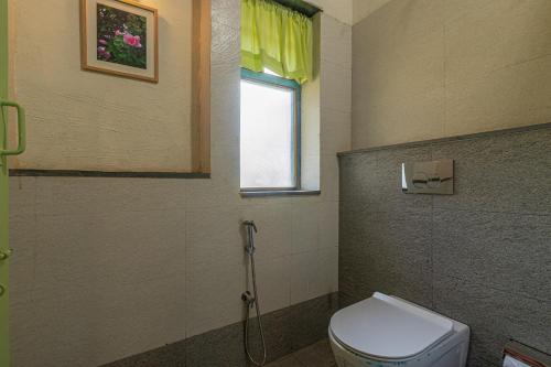 a bathroom with a toilet and a window at SaffronStays Lake House Marigold, Nashik - rustic cottages with private plunge pool in Nashik