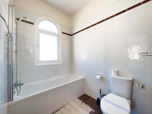 een badkamer met een toilet, een bad en een raam bij Villa Rea in Protaras