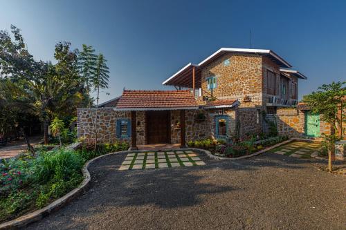 a brick house with a driveway in front of it at SaffronStays Lake House Marigold, Nashik - rustic cottages with private plunge pool in Nashik
