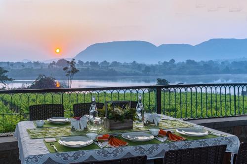 a dinner table with a view of a river at SaffronStays Lake House Marigold, Nashik - rustic cottages with private plunge pool in Nashik