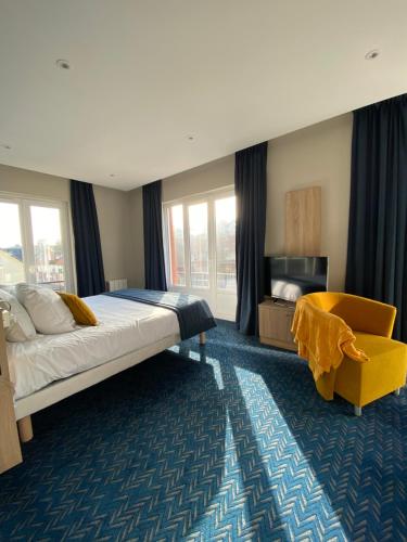 a bedroom with a large bed and a yellow chair at L'Huitrière in Quiberville