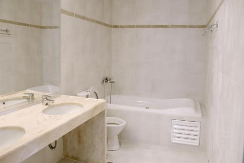 a white bathroom with two sinks and a toilet at Mohlos Villas in Mochlos