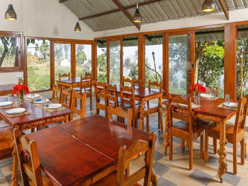 une salle à manger avec des tables et des chaises en bois dans l'établissement DEVASHOLA HOMESTAY, à Coonoor