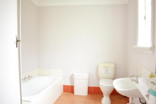 a bathroom with a tub and a toilet and a sink at Fairbridge Village in Pinjarra