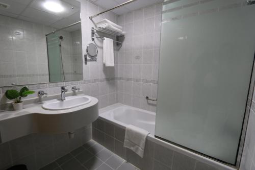 uma casa de banho branca com um lavatório e uma banheira em NEW CALIFORNIA HOTEL no Dubai