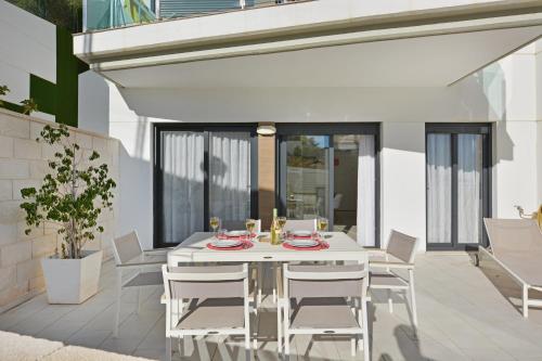 a white dining table and chairs on a patio at Beachfront Luxury Apartments by NRAS in Arenales del Sol