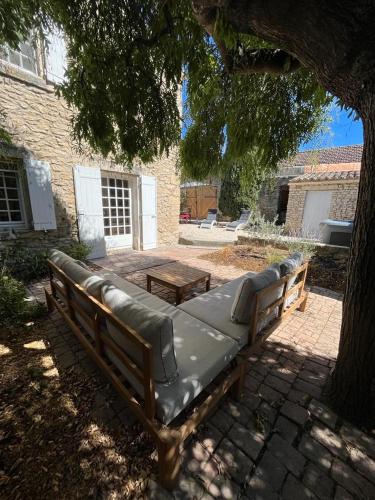 un banc assis sous un arbre dans une cour dans l'établissement La Maison de la Forge, à Gordes