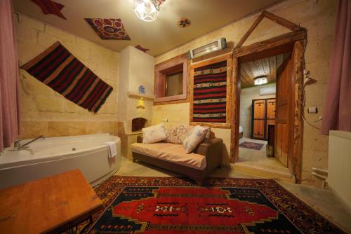 a living room with a tub and a couch in a room at Fosil Cave Hotel in Ortahisar