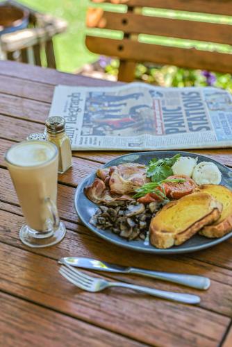 a plate of food and a drink on a wooden table at Peel Inn Hotel Nundle in Nundle