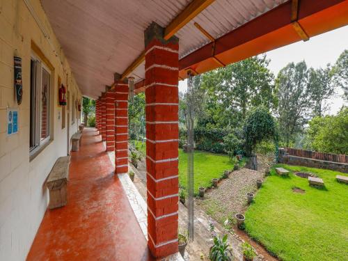 a porch of a house with a brick pillar at DEVASHOLA HOMESTAY in Coonoor