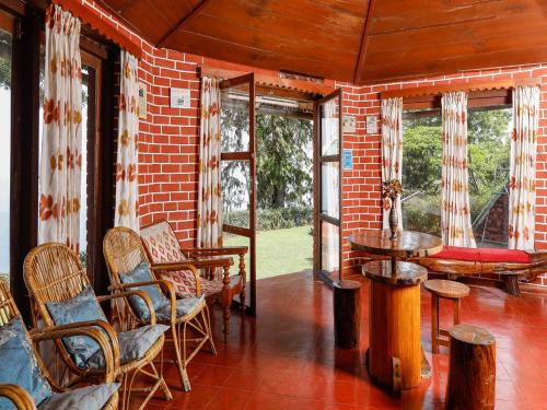 a porch with chairs and a table and windows at DEVASHOLA HOMESTAY in Coonoor