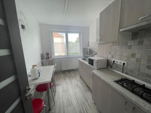 a kitchen with white cabinets and a table with red chairs at Lady M Apartment in Sighişoara