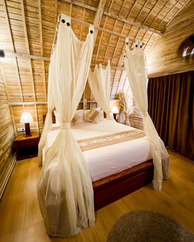 Schlafzimmer mit einem Bett mit weißen Moskitonetzen in der Unterkunft The Blooms Villas in Bedugul