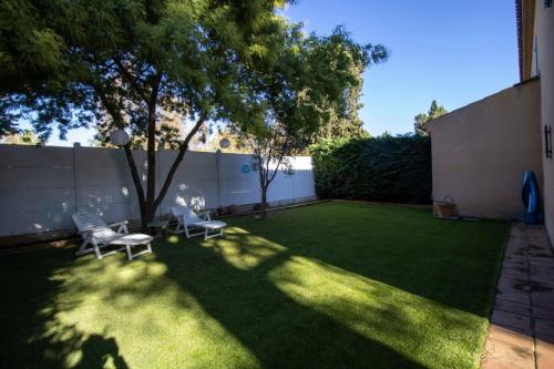 a backyard with a lawn with two chairs and a tree at Quiet villa with garden and terrace in Fréjus in Fréjus