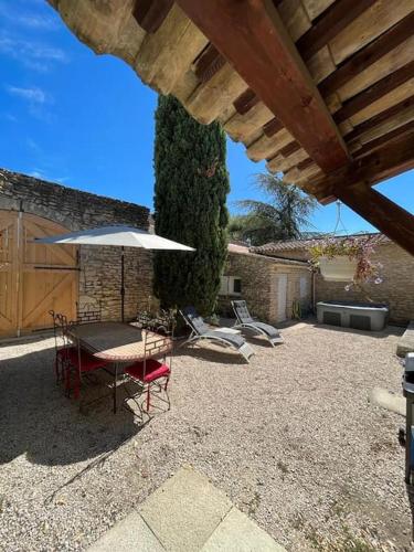 un patio avec une table, des chaises et un parasol dans l'établissement La Maison de la Forge, à Gordes