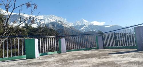 a white and green fence with mountains in the background at Yoga House in McLeod Ganj