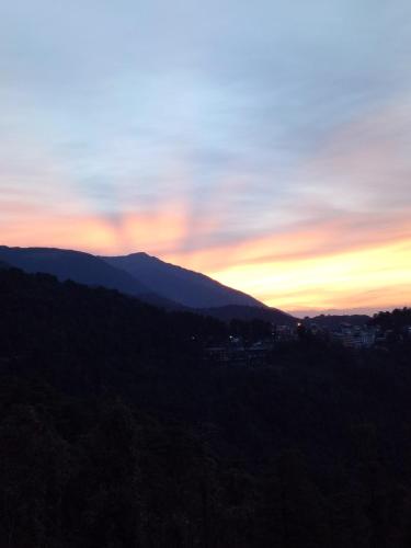 a sunset in the mountains with a city in the background at Yoga House in McLeod Ganj