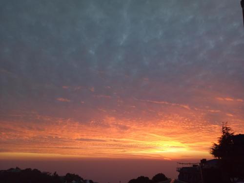 a sunset with the sun setting in the sky at Yoga House in McLeod Ganj