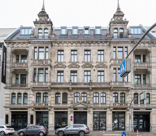 un grande edificio con macchine parcheggiate di fronte di numa I Arc Rooms & Apartments a Berlino