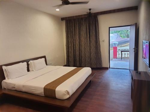 a bedroom with a bed and a sliding glass door at Adamo The Village in Matheran
