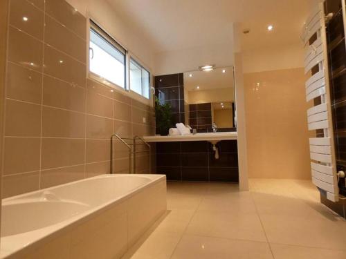 La salle de bains est pourvue d'une baignoire, d'un lavabo et d'un miroir. dans l'établissement Zenbreak Villa La Hourniere Sainte Marie de Gosse no01, à Port-de-Lanne